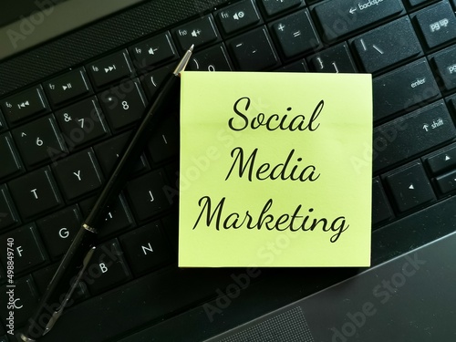 Social media marketing written on sticky note with a pen and keyboard.