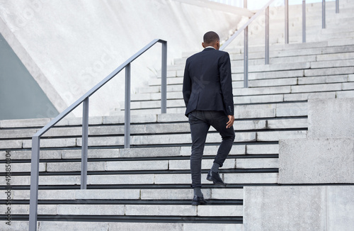 Walking up to success. Shot of an unrecognizable businessman walking up stairs in the city. © Michael Cunningham/peopleimages.com
