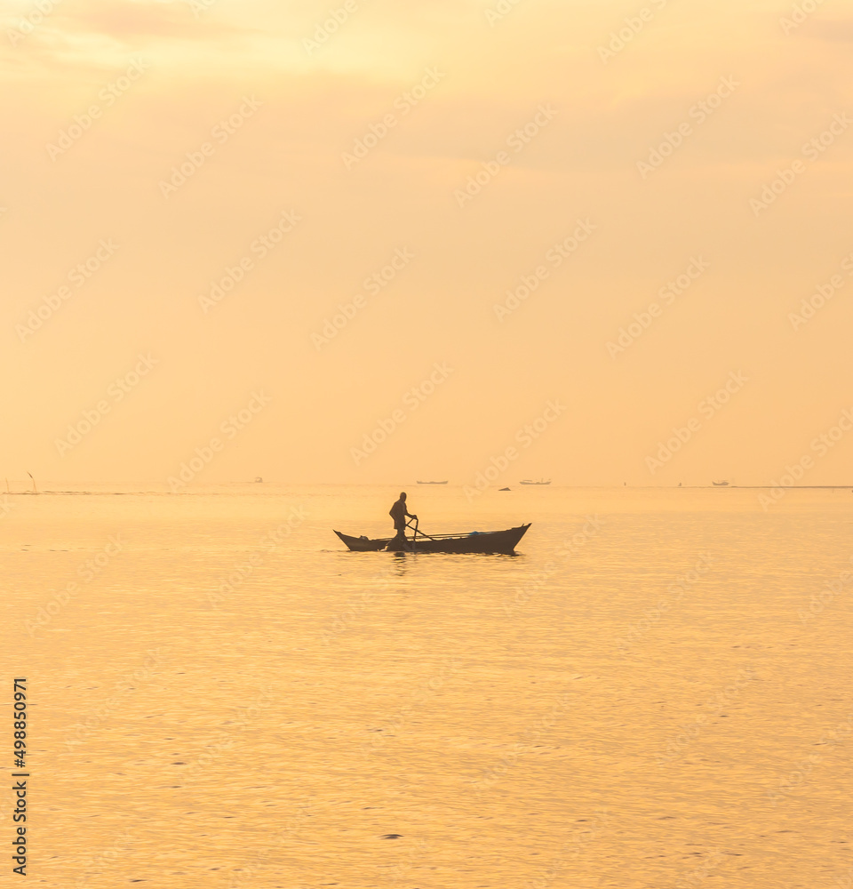 Silhouette of people with sea view and boats at sunrise in Medan, Indonesia, 2022