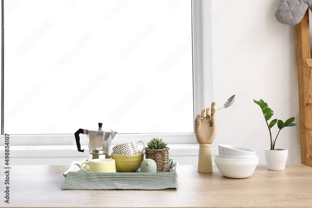 Tray with clean tableware, coffee pot and houseplant on counter in interior of modern kitchen Tray with clean tableware, coffee pot and houseplant on counter in interior of modern kitchen