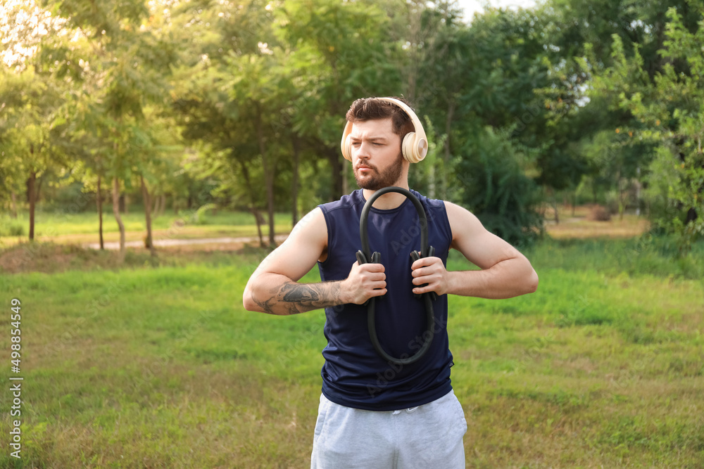 Sporty young man exercising with isotonic ring in park Sporty young man exercising with isotonic ring in park