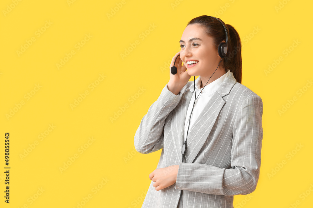 Pretty young businesswoman with headset on yellow background Pretty young businesswoman with headset on yellow background