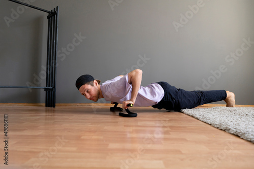 young guy doing push-ups fitness exercise on the floor at home
