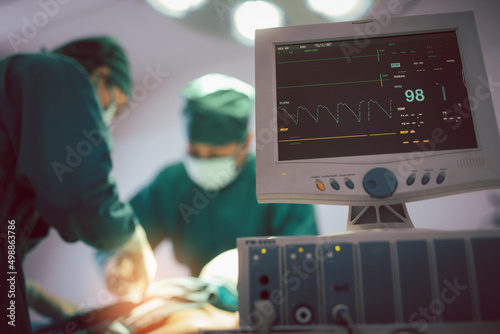 Monitor screen for a medical defibrillator or emergency heart pump, showing vital signs, heart rate, slow beating pulse of a dying coma patient in a hospital ICU room