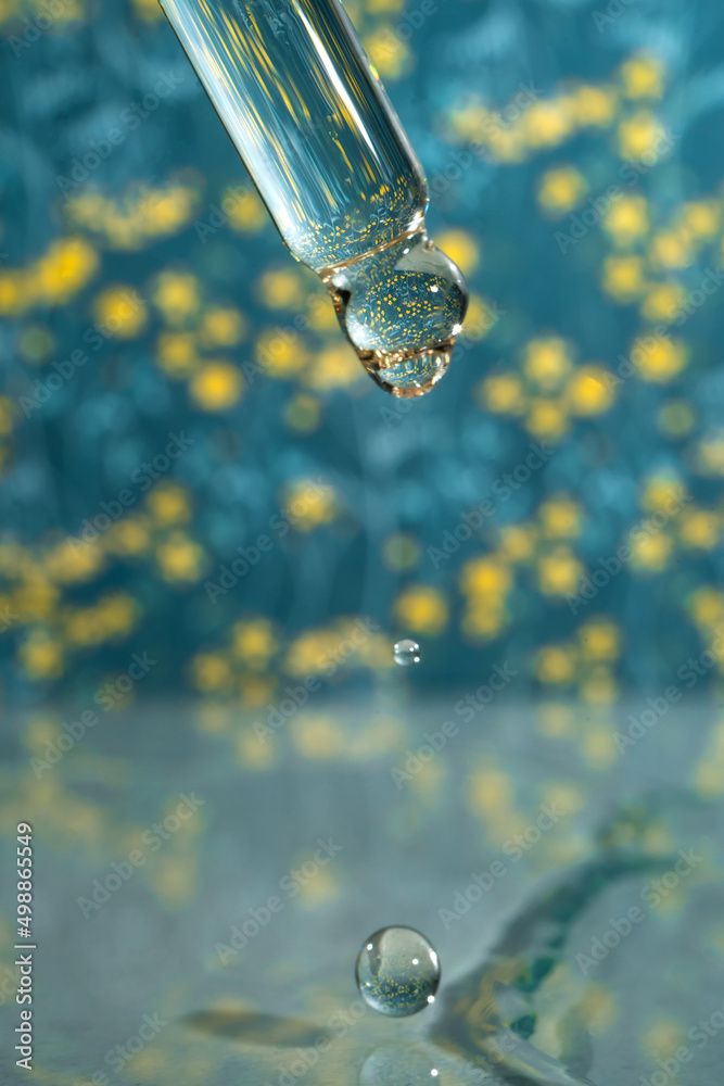 A dripping pipette with a drop of cosmetics gel. A dripping pipette with a drop of cosmetics gel.