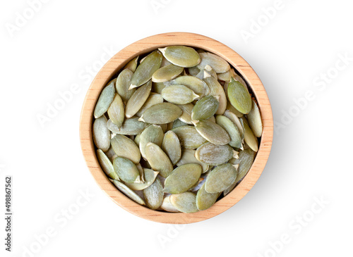 Pumpkin seeds in wooden bowl isolated on wooden table background. Top view. Flat lay.