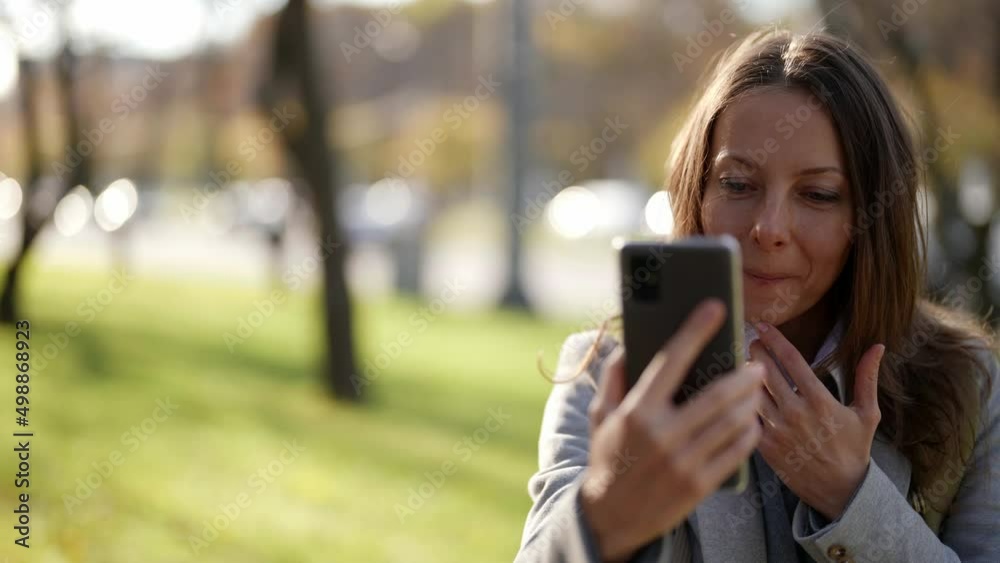 Attractive adult woman, uses the phone. Walk down the street in the city center. Travel with a tourist mobile phone outdoors. Portrait. Slow motion Attractive adult woman, uses the phone. Walk down the street in the city center. Travel with a tourist mobile phone outdoors. Portrait. Slow motion