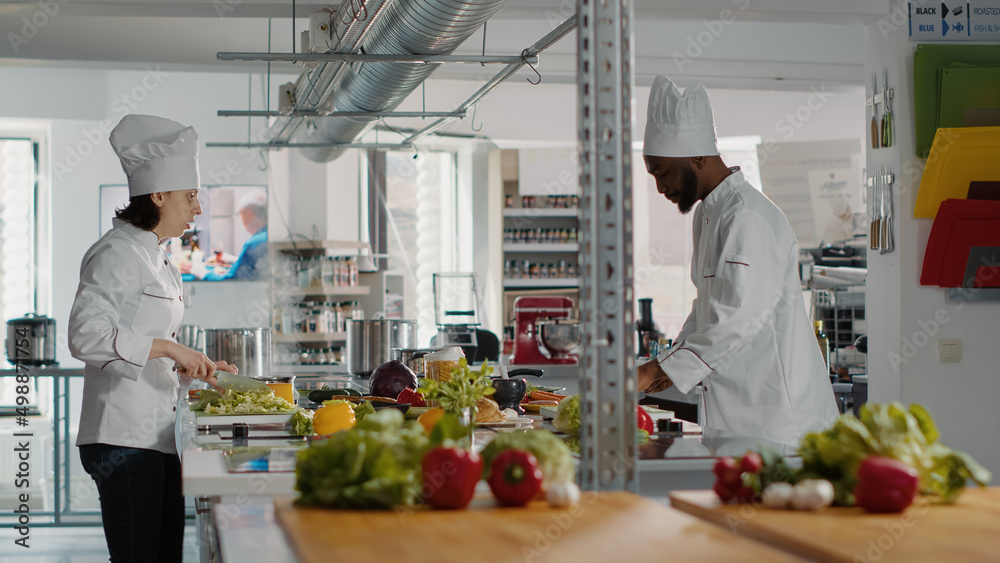 Man and woman cooking organic meal with celery and vegetables, doing gourmet dish preparations in kitchen, Professional team of authentic chefs making fresh food with gastronomic recipe. Man and woman cooking organic meal with celery and vegetables, doing gourmet dish preparations in kitchen, Professional team of authentic chefs making fresh food with gastronomic recipe.