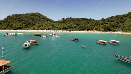 Aerial Pass Through Group of Colorful Red, Yellow and Blue Fishing Boats in Calm Tropical Waters Towards Campeche Island Beach Florianopolis Brazil Santa Catarina Drone 4k photo