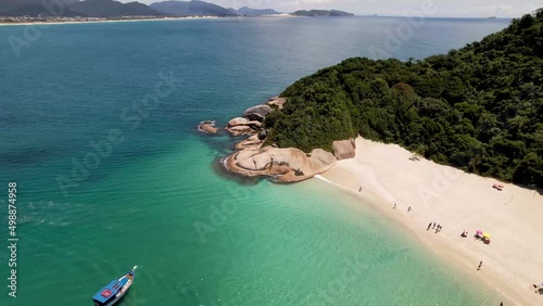 Aerial Orbit Around Smooth Rocky Peninsula in Vibrant Crystal Clear Tropical Turquoise Teal Blue  Waters of Campeche Island Florianopolis Brazil Summer Drone 4k photo