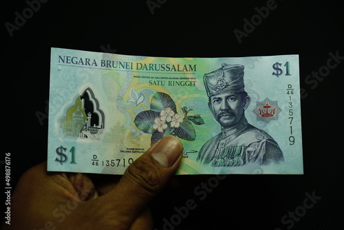 1 BND, one Brunei Darussalam Dollar money, was held by businessman, money concept isolated on black background photo