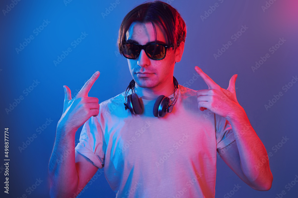 Showing gestures. Man standing in the studio with neon light