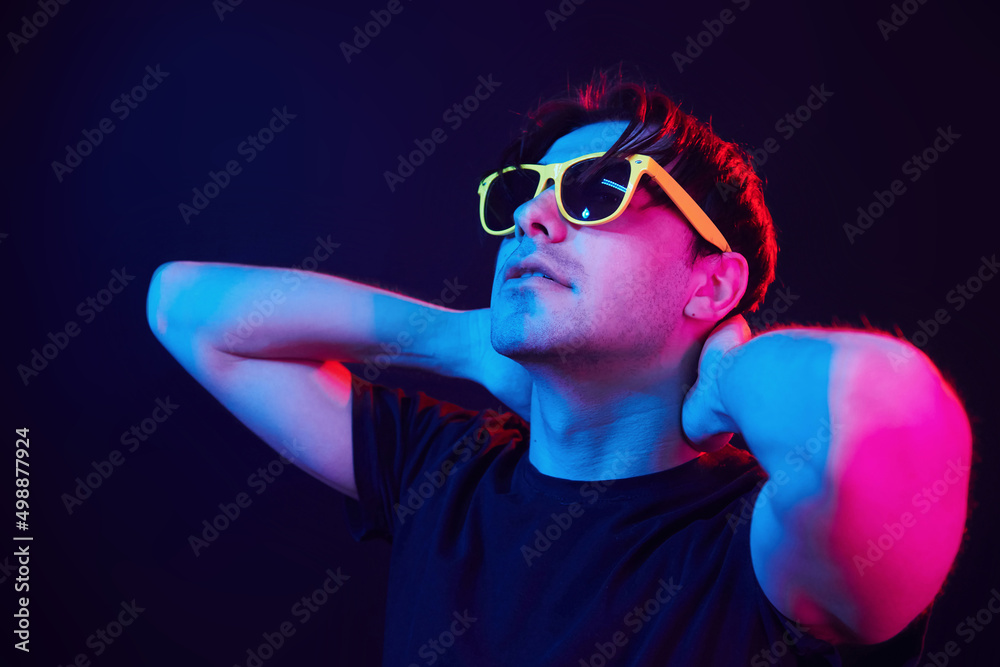In yellow sunglasses. Man standing in the studio with neon light In yellow sunglasses. Man standing in the studio with neon light