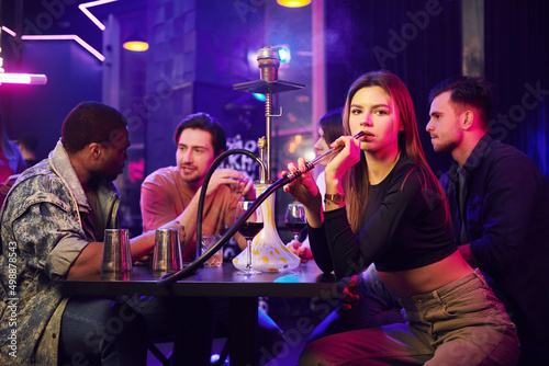 Hookah is on the table. Group of friends having fun in the night club together © standret