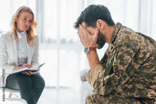 Side view. Soldier have therapy session with psychologist indoors photo