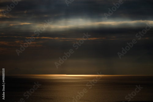 雲間からの光芒で反射する海面