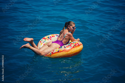 Beautiful young woman in the sea swims on an inflatable ring and has fun on vacation. Girl in a bright swimsuit at the sea under the sunlight © Дмитрий Ткачук