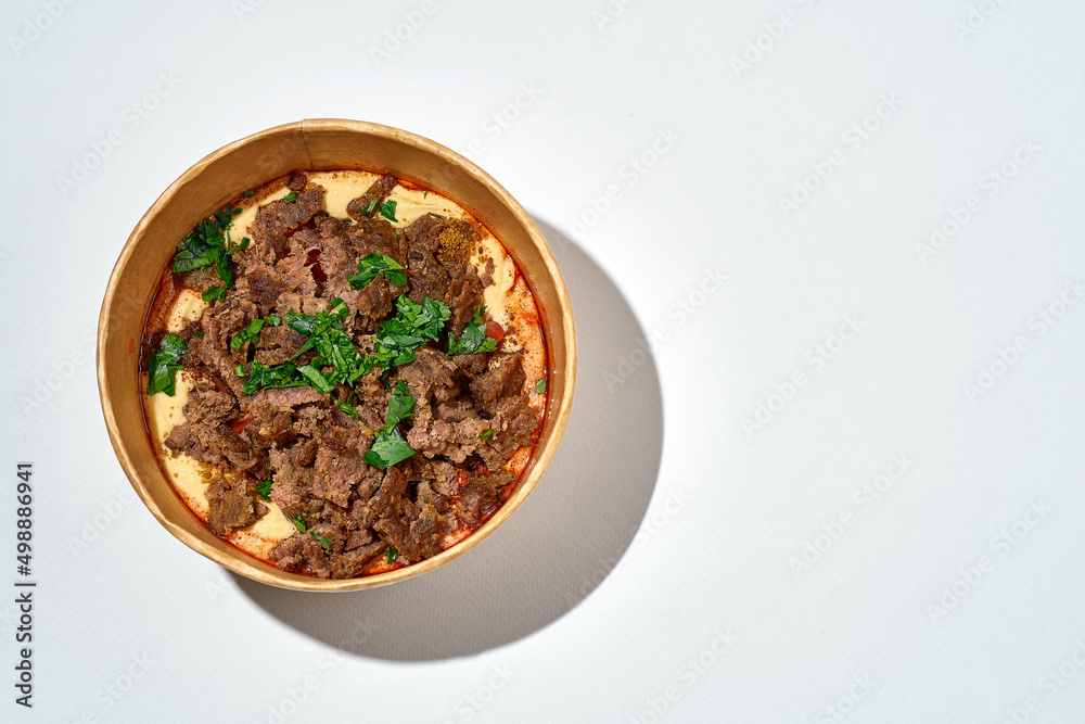 Hummus with beef kebab in a delivery box on an white background Hummus with beef kebab in a delivery box on an white background
