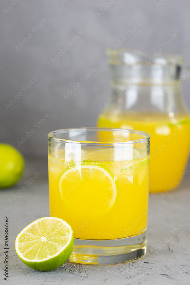 Fresh lemonade from oranges, limes and lemons in a glass on a gray background. Fresh lemonade from oranges, limes and lemons in a glass on a gray background.