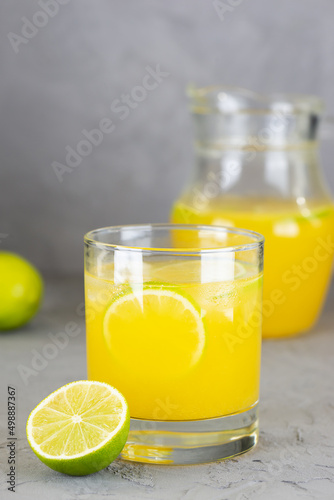Fresh lemonade from oranges, limes and lemons in a glass on a gray background.