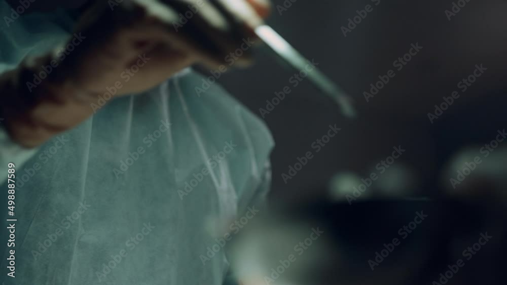 Confident surgeon operating patient in dark hospital emergency ward portrait.