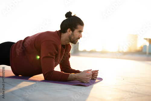 Young muscle man training outside. Fit sexy guy doing exercise outdoors.