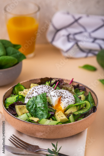 Healthy breakfast. Green salad with fresh avocado, poached egg and seeds chia. Vegetarian food concept. Copy space. Delicious appetizer, breakfast, lunch or brunch.