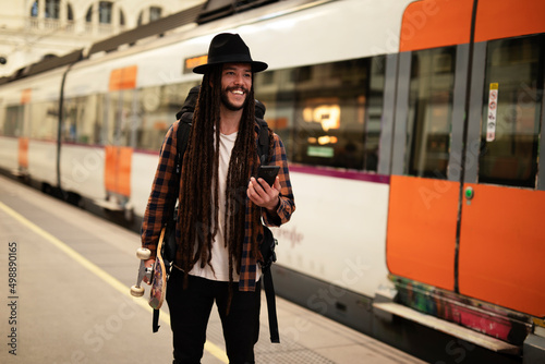 Handsome guy at railway station waiting for the train. Young man waiting to board a train photo