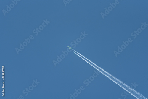 Airplane trail on a blue cloudless sky. Traveling by plane on vacation.