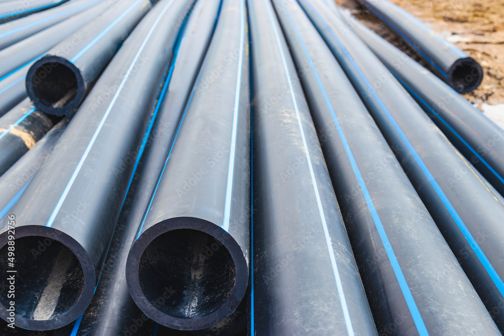Water pipes for drinking water supply lie on the construction site. Preparation for earthworks for laying an underground pipeline. Modern water supply systems for a residential city. Water pipes for drinking water supply lie on the construction site. Preparation for earthworks for laying an underground pipeline. Modern water supply systems for a residential city.