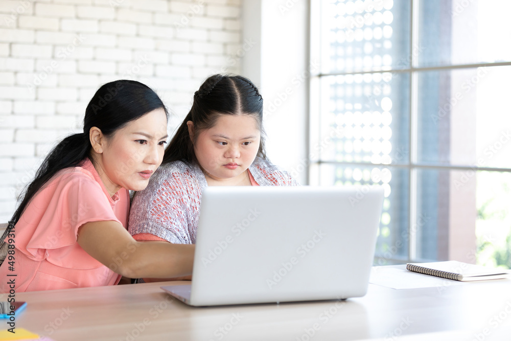 down syndrome teenage girl and her teacher using laptop computer together on a table down syndrome teenage girl and her teacher using laptop computer together on a table