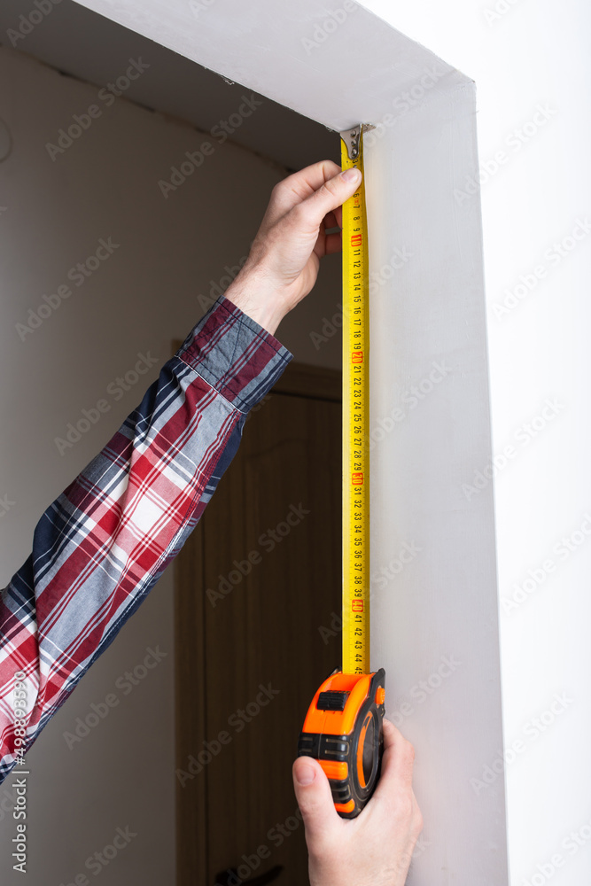 repairman builder measures the length of the doorway in the apartment, close-up