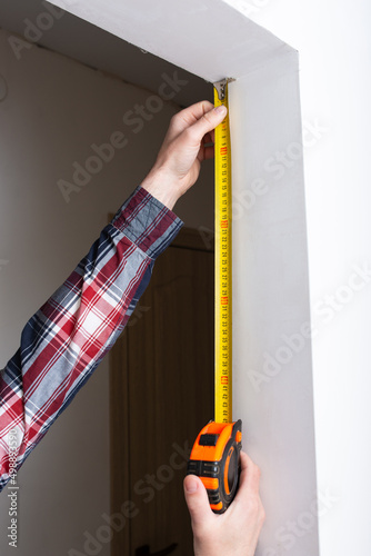 Obraz na płótnie repairman builder measures the length of the doorway in the apartment, close-up w salonie