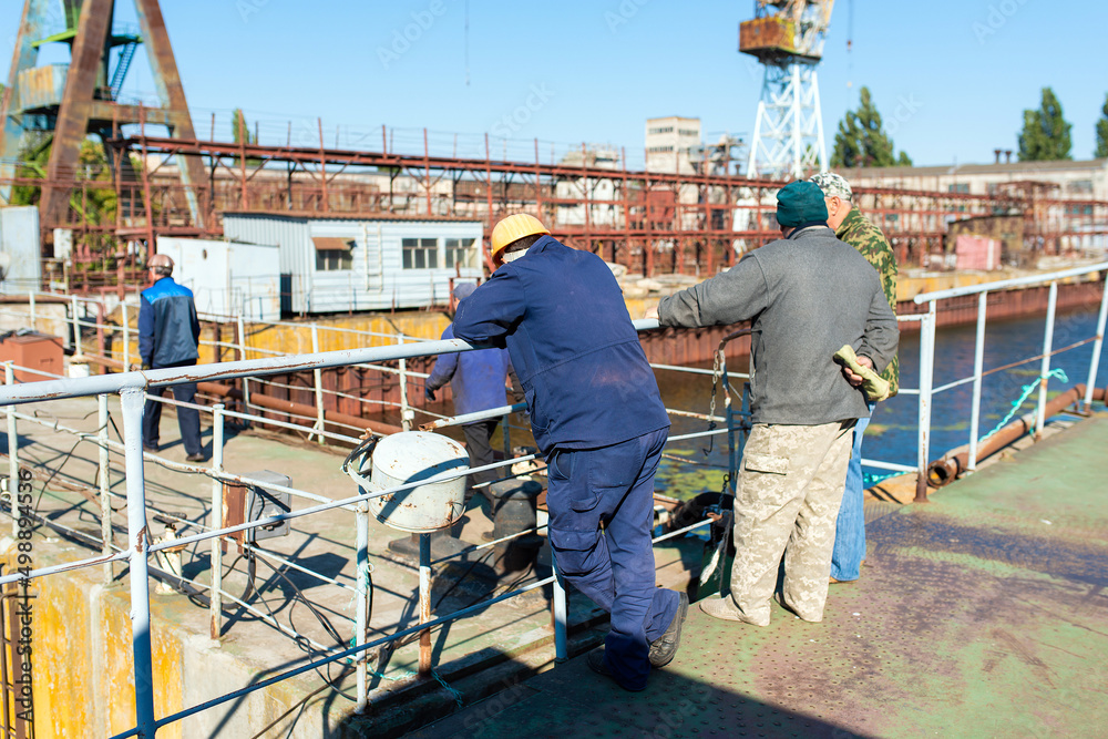 male shipyard workers on the background of cranes male shipyard workers on the background of cranes