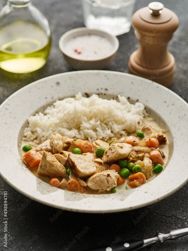 Stew of chicken and vegetables with mushroom cream sauce. Chicken fillets in creamy mushroom sauce with rice and green peas