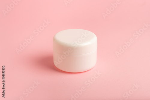 clean white plastic box with body cream on a pink background