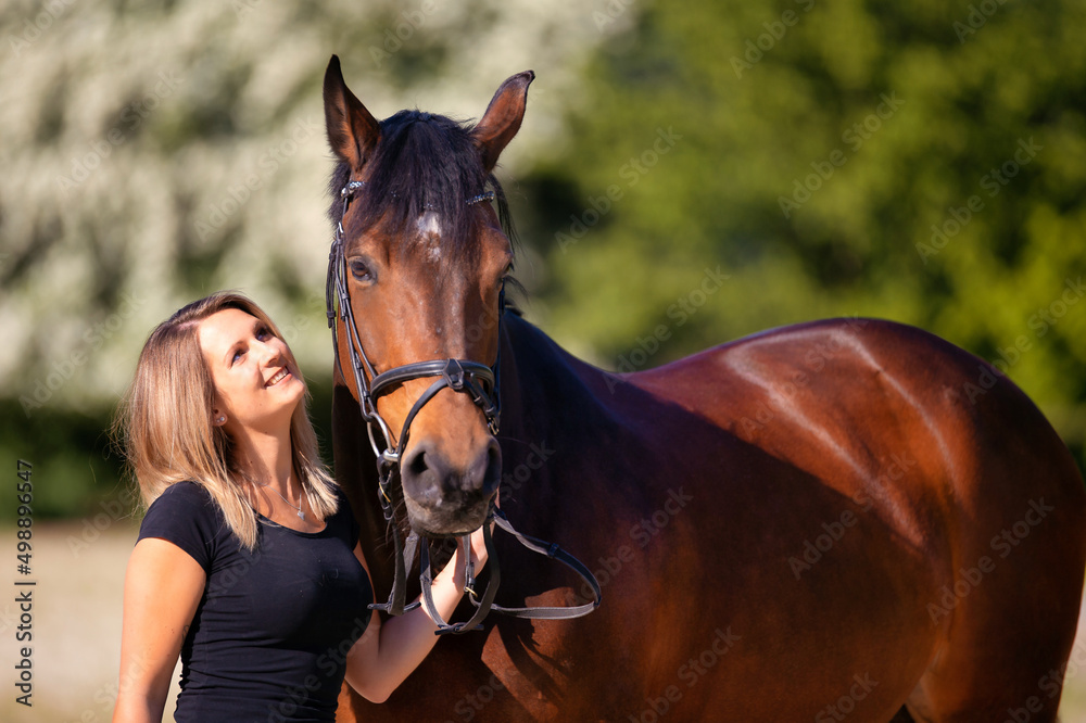 Obraz premium Young girl stands to the right of her horse and looks him lovingly in the eyes with a smile..
