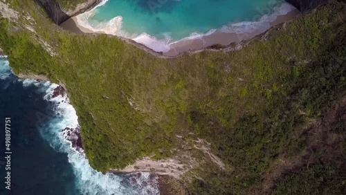 Dramatic aerial view flight high bird's eye view drone shot ofer edge cliff big waves 
Kelingking Beach at Nusa Penida in Bali Indonesia Jurassic Park. Cinematic nature view above by Philipp Marnitz photo