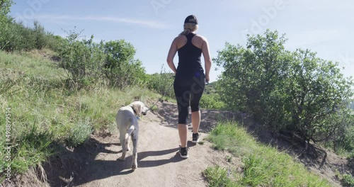 Girl walking golden retreiver puppy on dirt trail slowmo photo