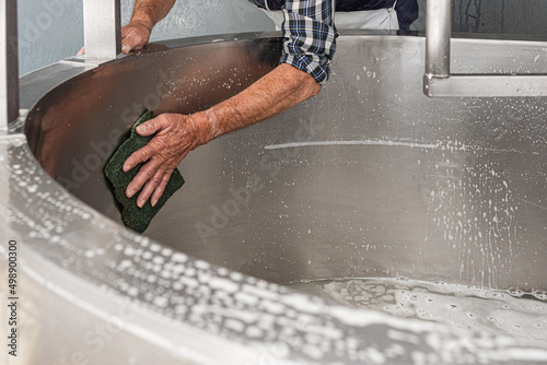 Принти на полотні unrecognisable older man scrubbing the inside of a metal curd container with a scouring pad