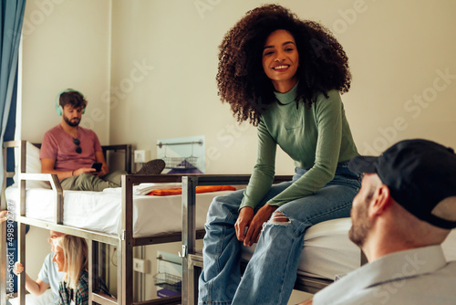 young people in dormitory spending free time - Brazilian girl with curly hair sitting on bunk bed talking to boy photo