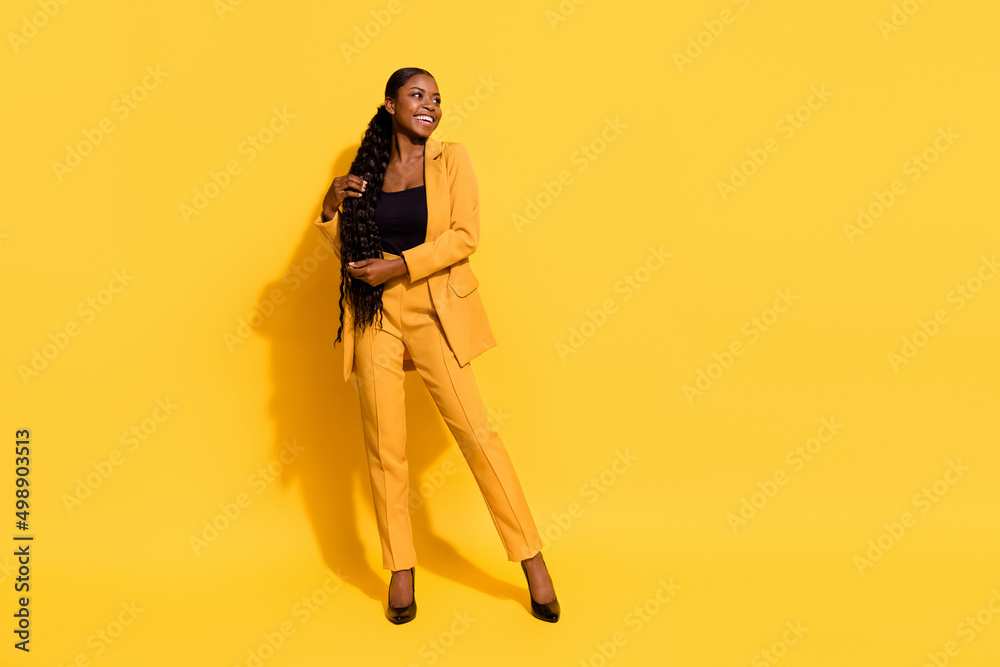 Full size photo of funny millennial lady stand look promo wear suit high heels isolated on yellow background Full size photo of funny millennial lady stand look promo wear suit high heels isolated on yellow background