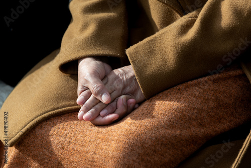 Konstfotografi A woman's hands are clasped with fingers interlocked and laying gently in a calm relaxed pose on her lap