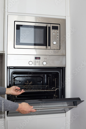 built in wall oven and microwave cabinet. Male hands open oven
