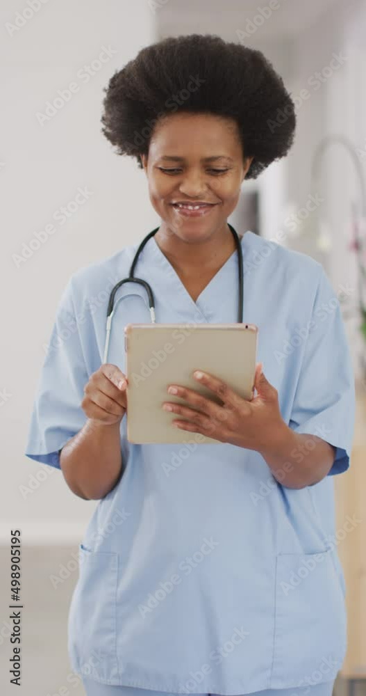 Vertical video of portrait of african american female doctor smiling and using tablet Vertical video of portrait of african american female doctor smiling and using tablet