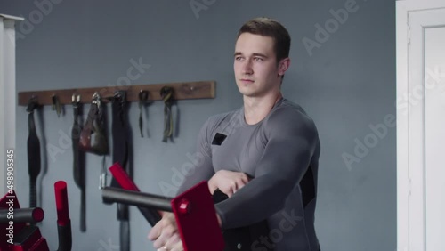 Handsome athletic man performing exercide on training apparatus machine in gym photo