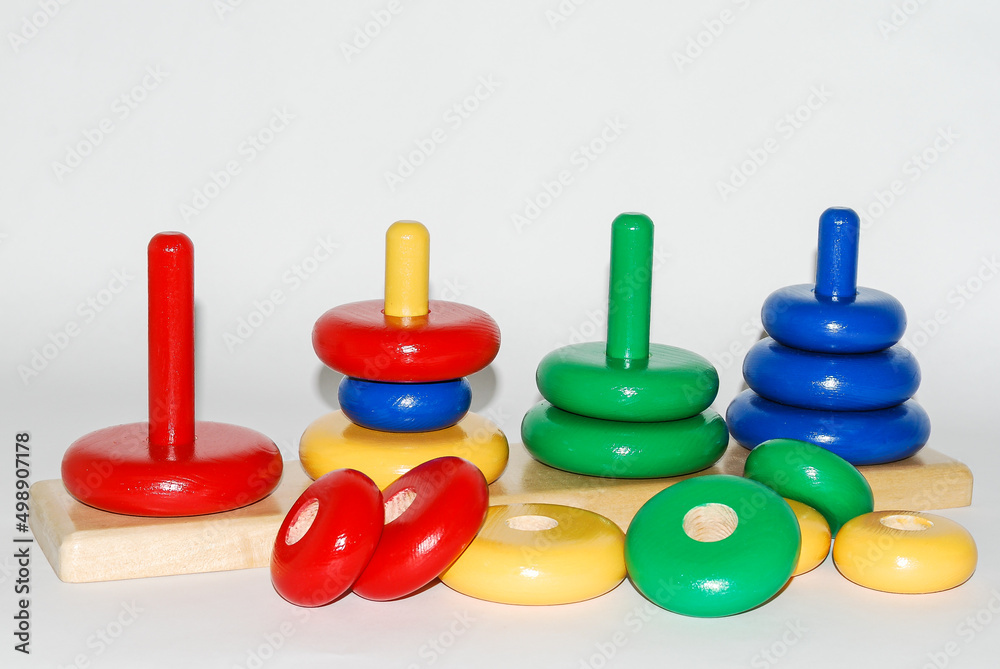 Wooden toy for baby, children isolated on white background. Rings of different colors and sizes placed on stakes of the same color. Wooden toy for baby, children isolated on white background. Rings of different colors and sizes placed on stakes of the same color.