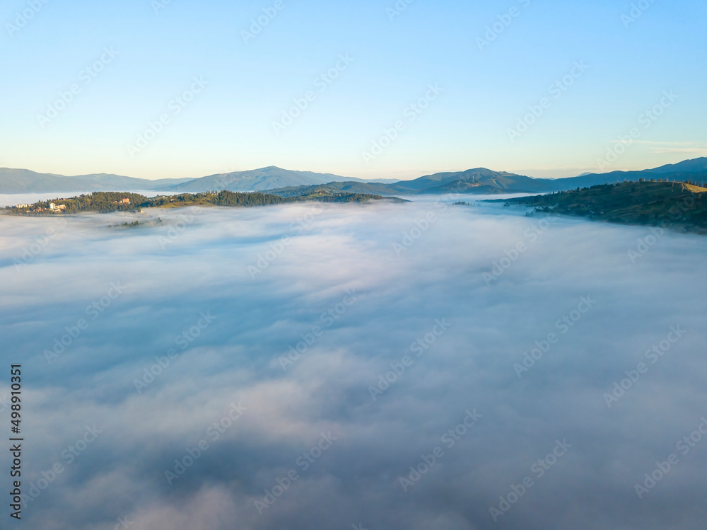 Sunny morning in the foggy Carpathians. A thick layer of fog covers the mountains. Aerial drone view. Sunny morning in the foggy Carpathians. A thick layer of fog covers the mountains. Aerial drone view.