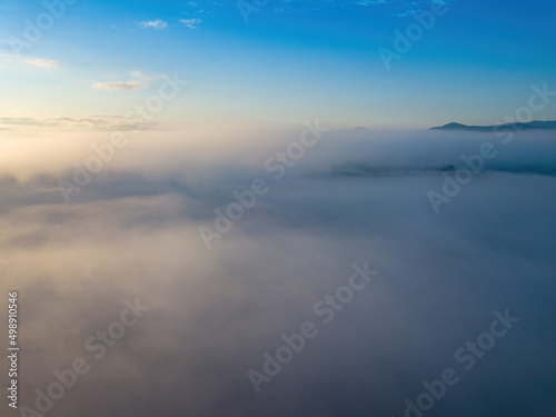 The rays of dawn over the fog in the Ukrainian Carpathians. Aerial drone view.