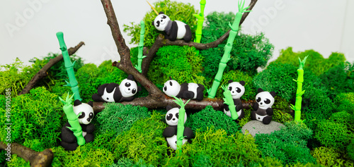 Funny homemade plasticine pandas in a stylized jungle.